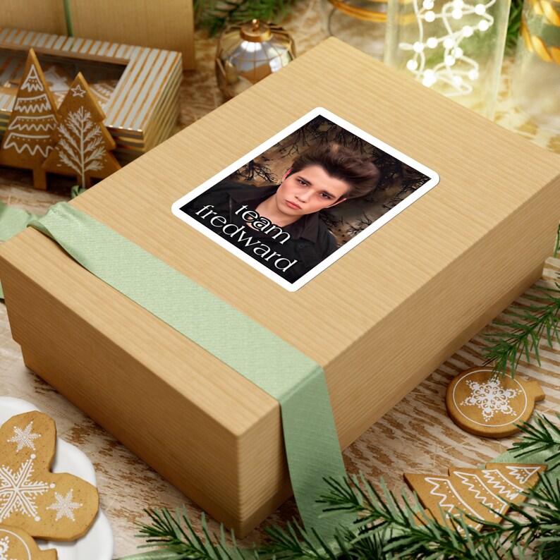 May include: A brown gift box with a green ribbon and a sticker that says "team fredward" with a picture of a young man with dark hair.