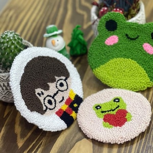 May include: Three handmade needle felted coasters. One features Harry Potter, one features a green frog, and one features a pink frog with a red heart.