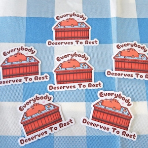 Peut inclure: Six autocollants colorés avec le texte "Tout le monde mérite de se reposer" et une illustration de dessin animé d'un hippopotame dans une baignoire.