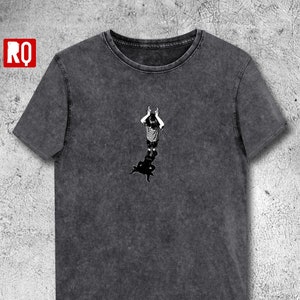 May include: A dark gray t-shirt with a black and white graphic of a person standing with their arms raised above their head. The graphic is centered on the shirt.