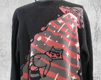 May include: Black sweater with a distressed hem. The sweater features a graphic of a raccoon wearing sunglasses and a space helmet, with a spaceship in the background. The graphic is in shades of pink, gray, and white.