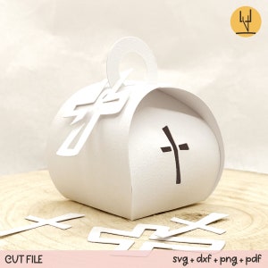 May include: White paper box with a cross cut-out design. The box has a handle and is decorated with a cross on the front. The box is surrounded by several smaller cross cut-outs.