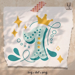 May include: A teal blue number one with a yellow crown on top. The number is decorated with white polka dots and three yellow stars. The background is a light beige with a shadow of leaves.