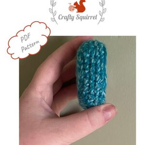 May include: A teal and white crocheted  coin purse or small pouch. The purse is held in a hand.