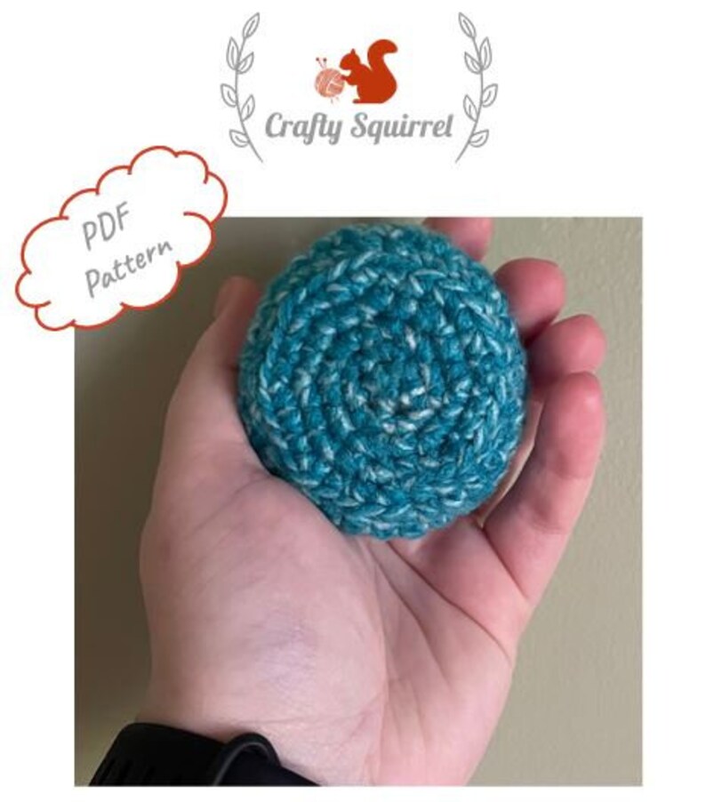 May include: A teal and white crocheted ball in a person's hand. The ball is made with a textured yarn and has a circular shape. The text "PDF Pattern" is visible in the background.