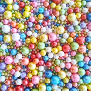 Peut inclure: Une image en gros plan d'une variété de vermicelles perlés colorés. Les vermicelles sont irisés et se déclinent en plusieurs couleurs, notamment le rose, le bleu, le vert, le jaune et le blanc.