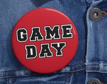 May include: Red button with white outline, featuring the text "GAME DAY" in black block letters.