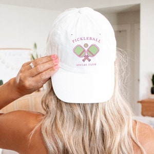 May include: White baseball cap with a pink and green pickleball logo that says "Pickleball Social Club".