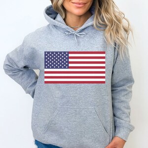 May include: A gray hooded sweatshirt with a printed American flag design. The flag is red, white, and blue.