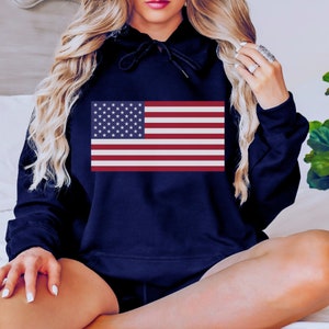 May include: A navy blue hooded sweatshirt with a red, white, and blue American flag printed on the front.