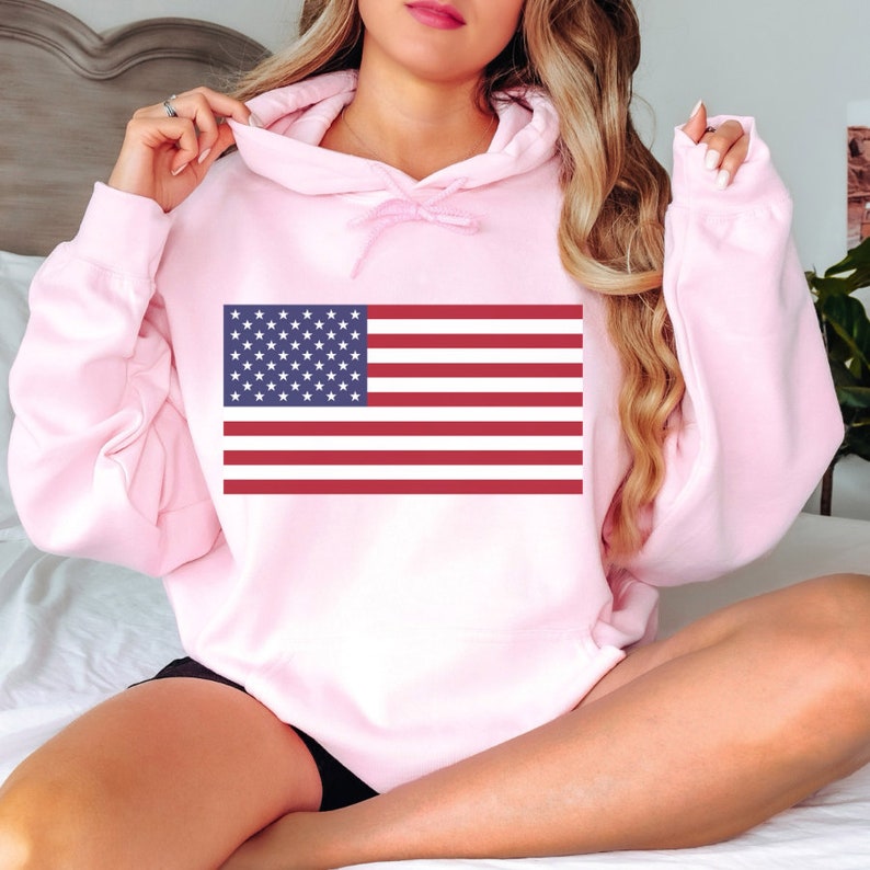 May include: A pink hooded sweatshirt with a graphic of the American flag printed on the front.