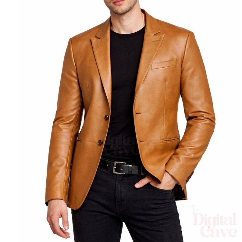 May include: A tan leather blazer with a two-button closure, notched lapels, and a chest pocket. The jacket is worn over a black shirt and paired with black jeans and a black belt. The blazer has a classic, tailored fit.