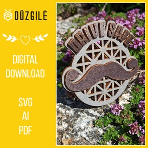 May include: A wooden sign with the words "Drive Safe" in a decorative font. The sign features a brown mustache and a geometric design in the center. The sign is sitting on a bed of green and purple flowers.