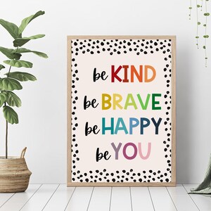 May include: A framed print with a white background and black polka dots. The print features the words "be kind", "be brave", "be happy", and "be you" in rainbow colors.
