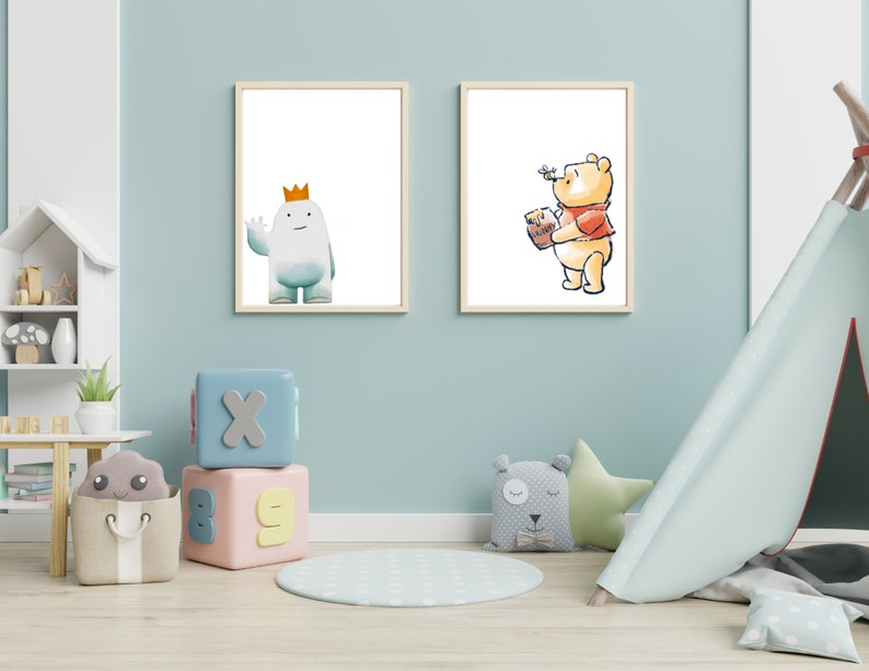 Op de afbeelding: Twee ingelijste illustraties van cartoonfiguren. De illustratie links toont een wit, rond personage met een kroon dat een blauw en wit pak draagt. De illustratie rechts toont een gele beer die een rood shirt draagt en een pot honing vasthoudt.