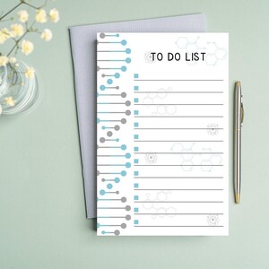 May include: A white to-do list notepad with a gray and blue geometric design on the left side. The right side has a list of blank lines with a gray check box next to each line. The text "TO DO LIST" is at the top of the notepad.