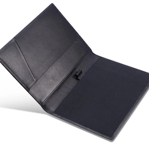 May include: Open black leather portfolio with a dark blue interior. The portfolio has a pocket on the left side and a pen holder. The cover is slightly angled, revealing the interior. The portfolio is designed for professional use.