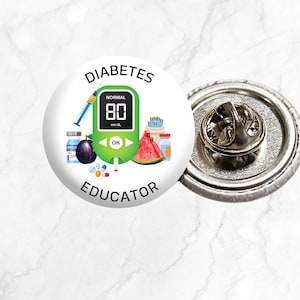 May include: A white button featuring a green and white diabetes meter, a syringe, a watermelon, a plum, and a bottle of insulin. The button reads "Diabetes Educator" in black text.