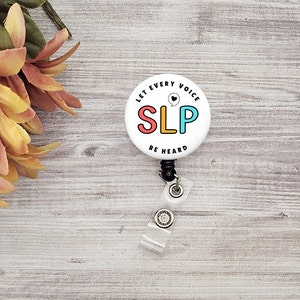 May include: White button with a black retractable badge reel. The button has the text "Let Every Voice" above the text "SLP" in colourful letters with a heart symbol. The text "Be Heard" is below the letters.
