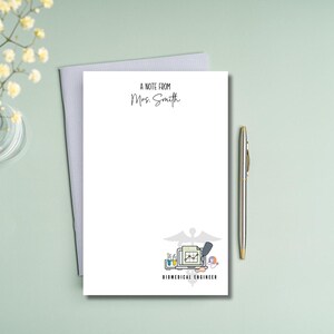 May include: A white notecard with a gray border. The text "A note from Mrs. Smith" is at the top of the card. The bottom of the card has a black and white illustration of a biomedical engineer's workspace with the text "Biomedical Engineer" underneath.