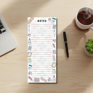 May include: A notepad with the word "NOTES" at the top, decorated with medical illustrations. It sits on a wooden desk alongside a laptop, a cup of tea, a pen, and a small succulent plant.