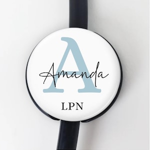 May include: A white stethoscope tag with a blue letter A and the name Amanda written in cursive. The tag also says LPN.