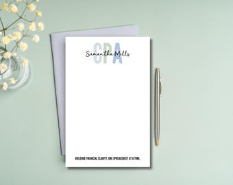 May include: A white notepad with a blue, green, and light blue CPA logo and the text "Samantha Mills" and "Building financial clarity, one spreadsheet at a time."