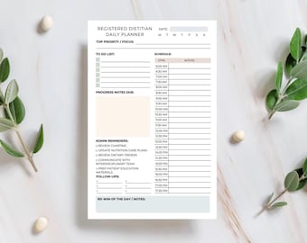 Könnte beinhalten: Ein weißer Tagesplaner für registrierte Ernährungsberater mit einem Zeitplan, einer To-Do-Liste und Admin-Erinnerungen. Der Planer enthält Abschnitte für Fortschrittsnotizen und Nachverfolgungen. Der Text ist schwarz.