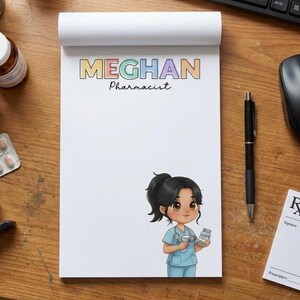 May include: A white notepad featuring the name "MEGHAN" in colourful letters and the word "Pharmacist" beneath. An illustration of a pharmacist in blue scrubs holding medicine bottles is on the bottom right.