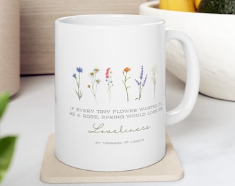 May include: White ceramic mug with a quote by St. Therese of Lisieux: "If every tiny flower wanted to be a rose, spring would lose its loveliness." The quote is surrounded by a watercolor illustration of various flowers.