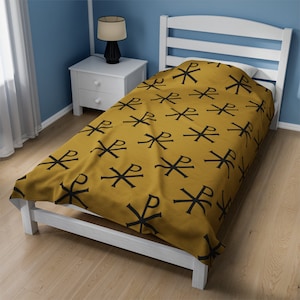 May include: A mustard yellow twin-sized bedspread with a black repeating pattern of the Chi Rho symbol.