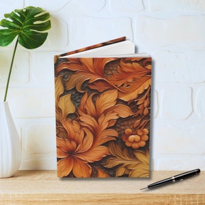 May include: A closed journal with a brown, orange, and gold floral design. The cover features a carved, embossed pattern of leaves and flowers.