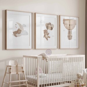 May include: Three framed prints featuring watercolour illustrations of brown bears. The first print depicts a bear sleeping on a crescent moon. The second print shows a bear holding balloons. The third print shows a bear in a hot air balloon.