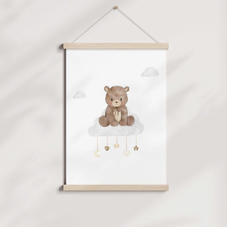 May include: A brown teddy bear sitting on a white cloud with gold stars and hearts hanging from it. The background is white.