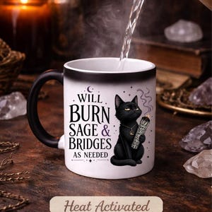 Peut inclure: Mug &agrave; activation thermique avec anse et bord noirs. Le mug pr&eacute;sente un chat noir tenant de la sauge, avec le texte "WILL BURN SAGE & BRIDGES AS NEEDED". Les mots "Heat Activated" sont &eacute;galement visibles.