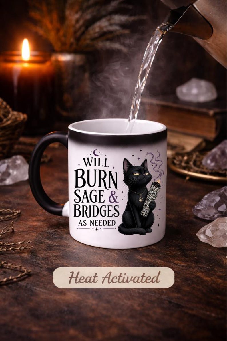Peut inclure: Mug &agrave; activation thermique avec anse et bord noirs. Le mug pr&eacute;sente un chat noir tenant de la sauge, avec le texte "WILL BURN SAGE & BRIDGES AS NEEDED". Les mots "Heat Activated" sont &eacute;galement visibles.