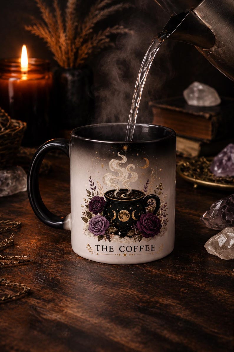 Op de afbeelding: Een zwart-witte koffiemok met een bloemen- en hemels ontwerp. De mok heeft paarse rozen, halve manen en de tekst "THE COFFEE". Er wordt heet water in de mok gegoten, waardoor stoom ontstaat.