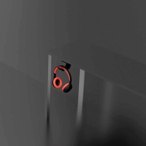 May include: Black headphones with red earcups hanging from a desk.