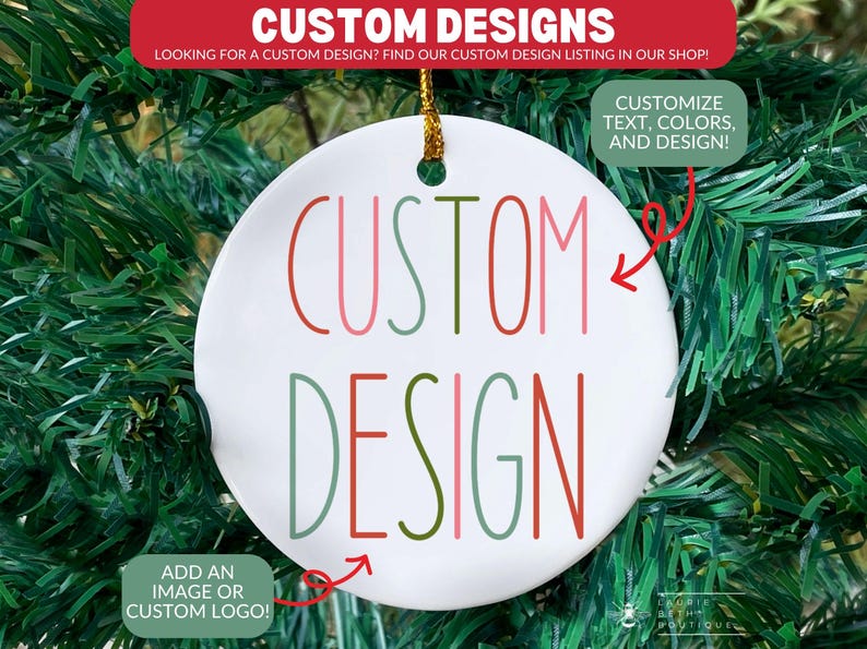 May include: A round white ceramic ornament with a gold hanging string. The text CUSTOM DESIGN is printed in the center in a multi-colored sans-serif font using shades of red, pink, and sage green. The ornament features a small hole at the top.