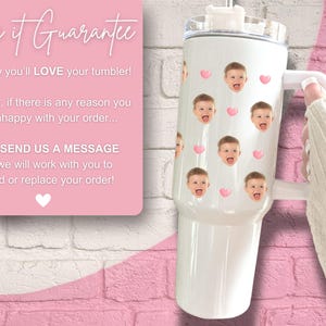 Peut inclure: Un gobelet en acier inoxydable blanc avec un couvercle et une poign&eacute;e. Le gobelet est d&eacute;cor&eacute; d'un motif de c&oelig;urs roses et d'une image r&eacute;p&eacute;t&eacute;e d'un visage d'enfant. Le texte "Love it Guarantee" est visible sur un fond rose.
