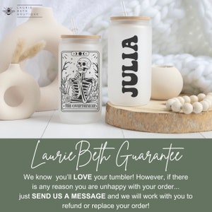 May include: Two frosted glass tumblers with lids and straws. One tumbler has a black and white illustration of a skeleton with the text "The Overthinker." The other tumbler has the name "Julia" written in black. The tumblers are sitting on a wooden surface.