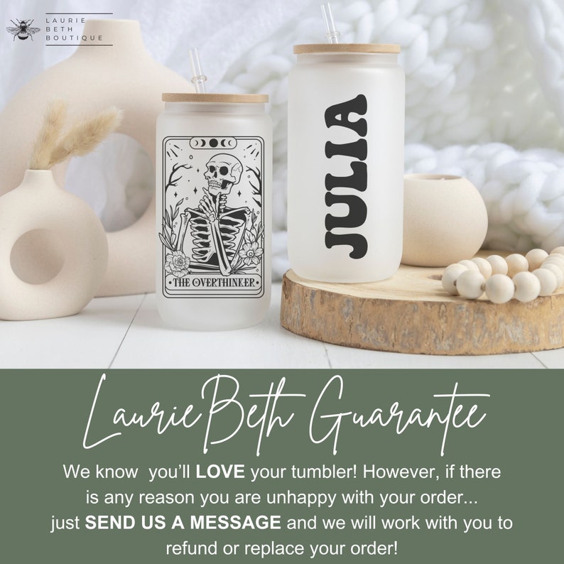 May include: Two frosted glass tumblers with lids and straws. One tumbler has a black and white illustration of a skeleton with the text "The Overthinker." The other tumbler has the name "Julia" written in black. The tumblers are sitting on a wooden surface.