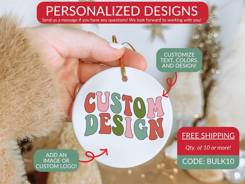 Op de afbeelding: Een rond wit keramieken ornament met de tekst CUSTOM DESIGN in een golvend, meerkleurig lettertype met tinten roze, rood en groen. Het ornament is voorzien van een gouden ophangkoord aan de bovenkant en wordt gepresenteerd als aanpasbaar product.
