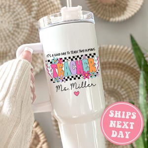 May include: White stainless steel tumbler with a pink, blue, and green "Teacher" design and the text "It's a good day to teach tiny humans". The tumbler also has the name "Ms. Miller" and a pink heart.