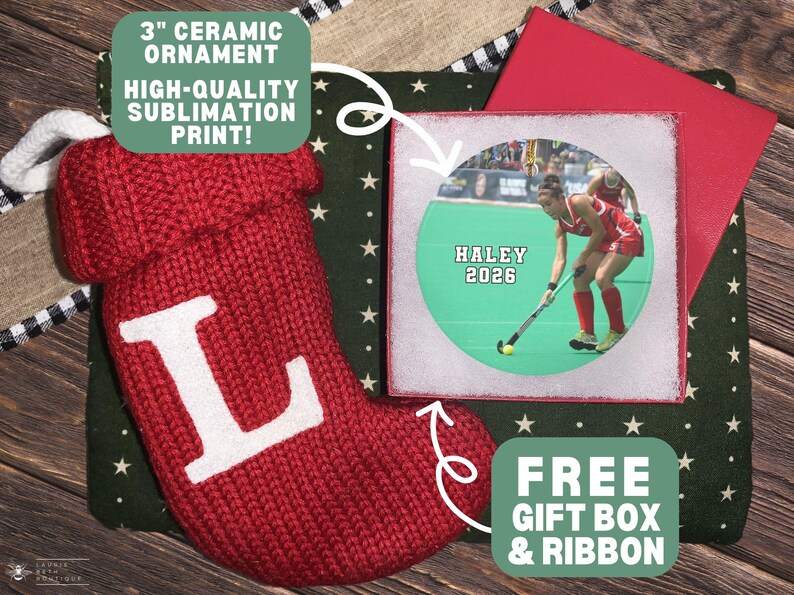May include: A 3-inch ceramic ornament featuring a sublimation print of a field hockey player with the text HALEY 2026, accompanied by a red knit stocking with a white letter L, a dark green star-patterned fabric, and a red gift box.