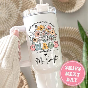 May include: White stainless steel tumbler with a floral design and the text "Problem solving super woman chaos coordinator Ms. Smith".