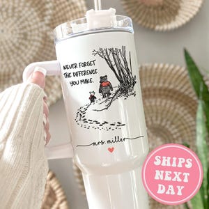May include: White stainless steel tumbler with a black and white illustration of Winnie the Pooh and Piglet walking in the woods. The tumbler has a black lid and a black handle. The text "Never forget the difference you make." is printed on the tumbler. The text "mrs. miller" is printed on the tumbler below the illustration. A pink circle with the text "SHIPS NEXT DAY" is in the lower right corner of the image.
