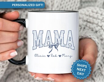 May include: White ceramic mug with a black rim and handle. The mug has a blue and white design that says "MAMA" with a blue bow underneath. The text "Olivia  ♥  Rob  ♥  Mary" is written below the bow.