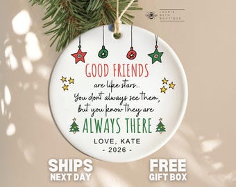 May include: A round white ceramic ornament featuring red, green, and yellow illustrations of stars and Christmas trees. The text reads: GOOD FRIENDS are like stars... You don't always see them, but you know they are ALWAYS THERE. LOVE, KATE - 2026.