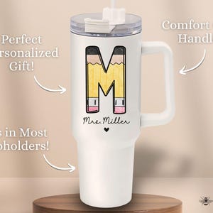 May include: White stainless steel travel mug with a black and yellow pencil design that spells out the letter "M". The mug has a black handle and a clear lid with a straw. The text "Mrs. Miller" is printed on the mug.